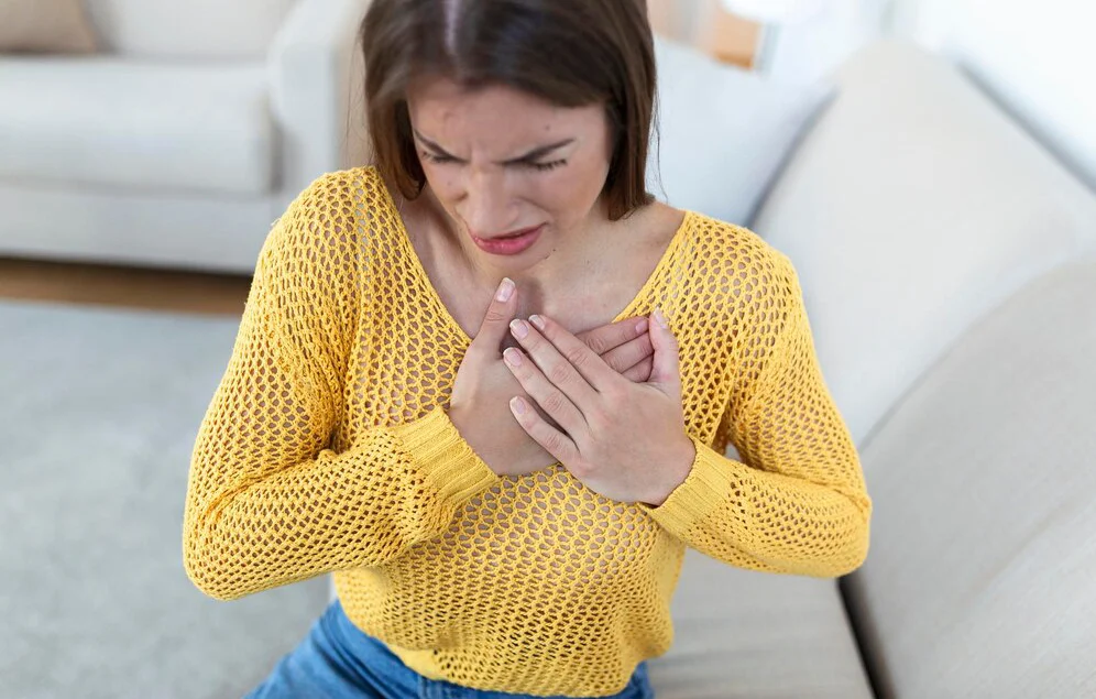 Mujer con fuerte dolor en el pecho debido a las palpitaciones irregulares