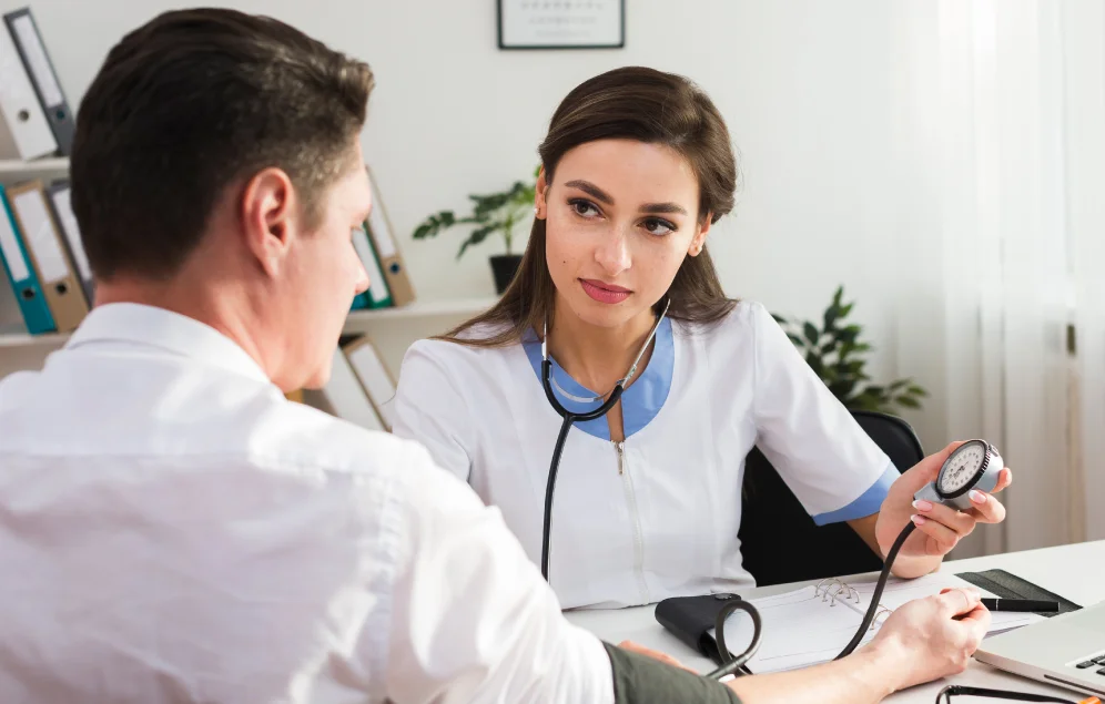 Una doctora toma la presión arterial a un paciente en un consultorio médico, enfocándose en la lectura del tensiómetro